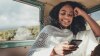 Mujer joven sonriente lee en su celular el Blog de IELTS Colombia para presentar la prueba de inglés con el British Council
