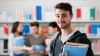 Young man smiles while holding some IELTS preparation books in Colombia