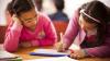 Dos niñas trabajan juntas en clase y toman notas