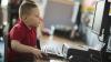 Un niño sentado frente a un computador