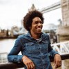 Hombre sonríe frente al Tower Bridge en Londres. Gracias a los resultados de su test de inglés IELTS UKVI vive en Reino Unido
